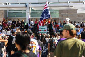 Protesters wave flags at an outdoor gathering.