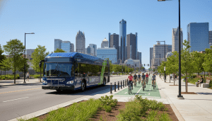 A modern electric bus and cyclists utilizing Detroit sustainable transportation infrastructure.