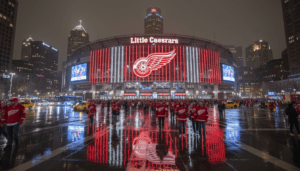 A vibrant crowd at Little Caesars Arena celebrating Detroit Red Wings news and team performance.